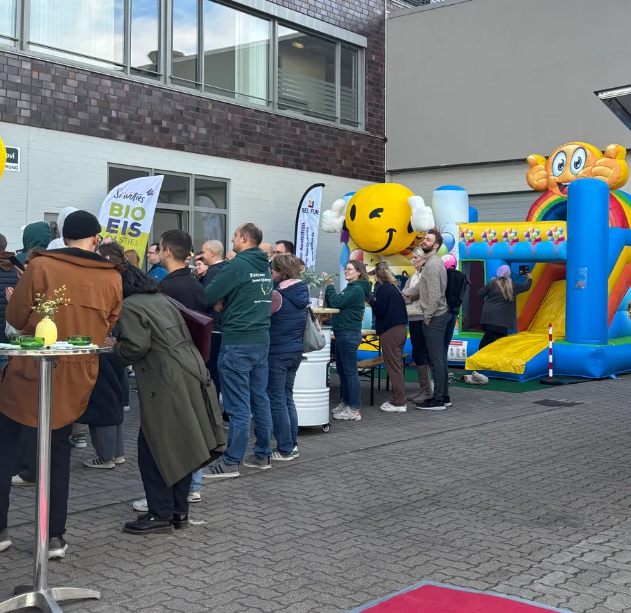 People socializing near inflatable castle outdoors.