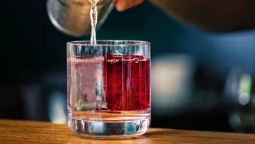 Liquor being poured into a glass on a bar.
