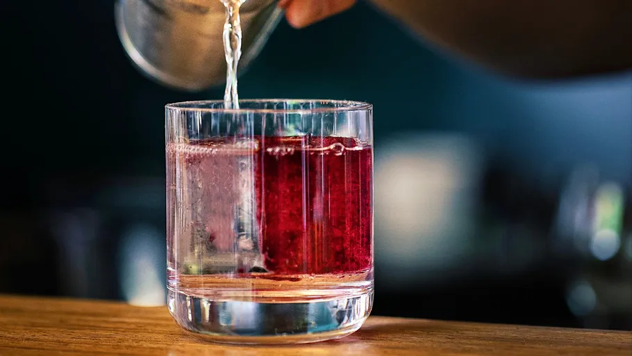 Liquor being poured into a glass on a bar.
