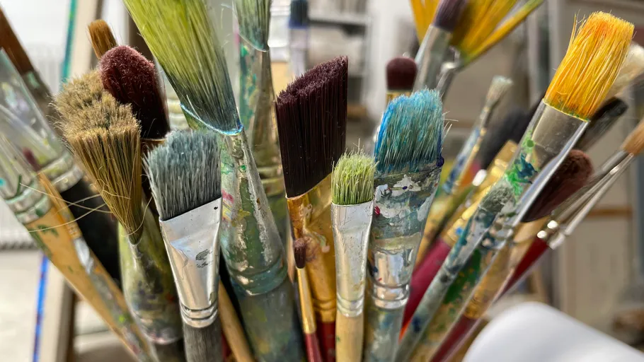 Colorful paintbrushes with paint in a holder.