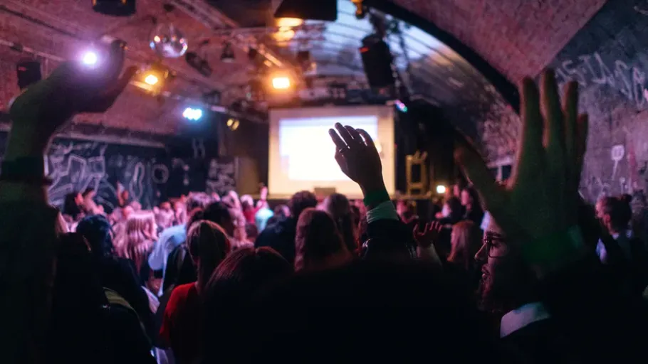 Crowd raising hands in a dark venue.