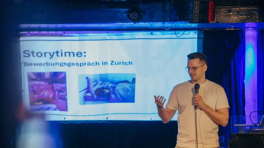 Mann hält Vortrag auf Bühne mit Präsentationsfolie.