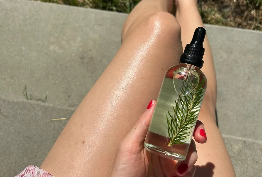 Hand holding bottle, person sitting outdoors.