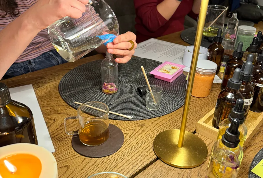 Person gießt Flüssigkeit in ein Glas auf Tisch.