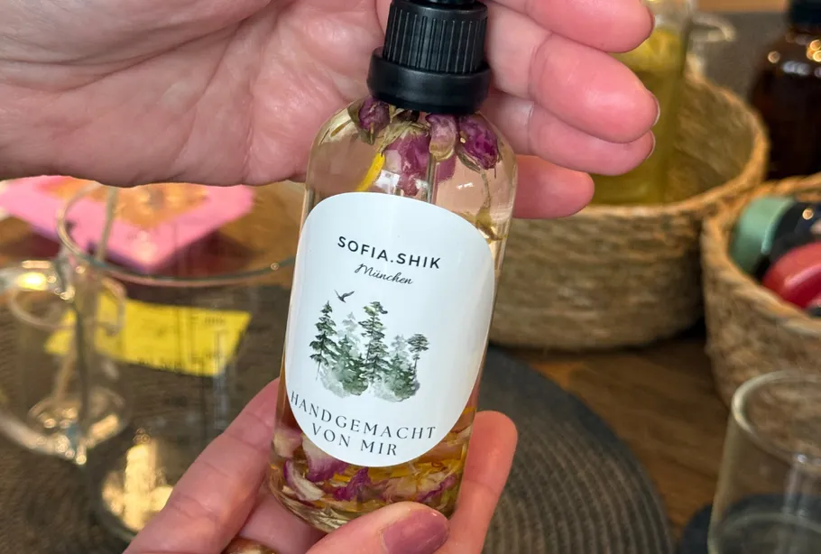 Hände halten eine Flasche mit Blumeninhalt.