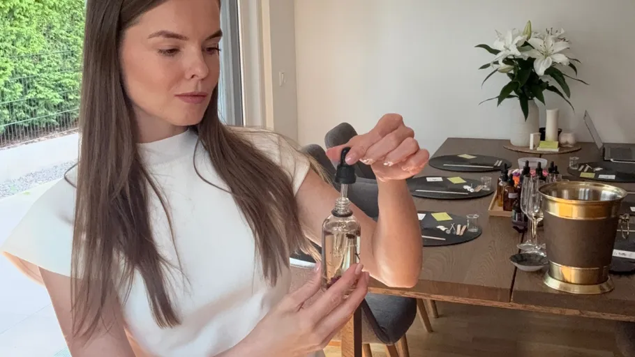 Woman using dropper with glass bottle indoors.