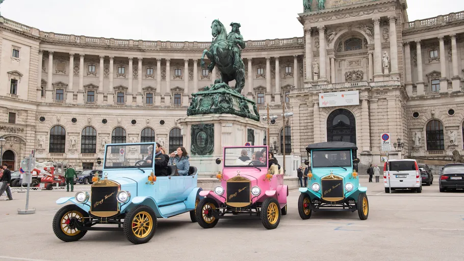 Bunte Oldtimer vor historischem Gebäude.