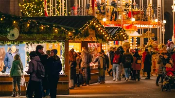 People browsing Christmas market stalls at night.
