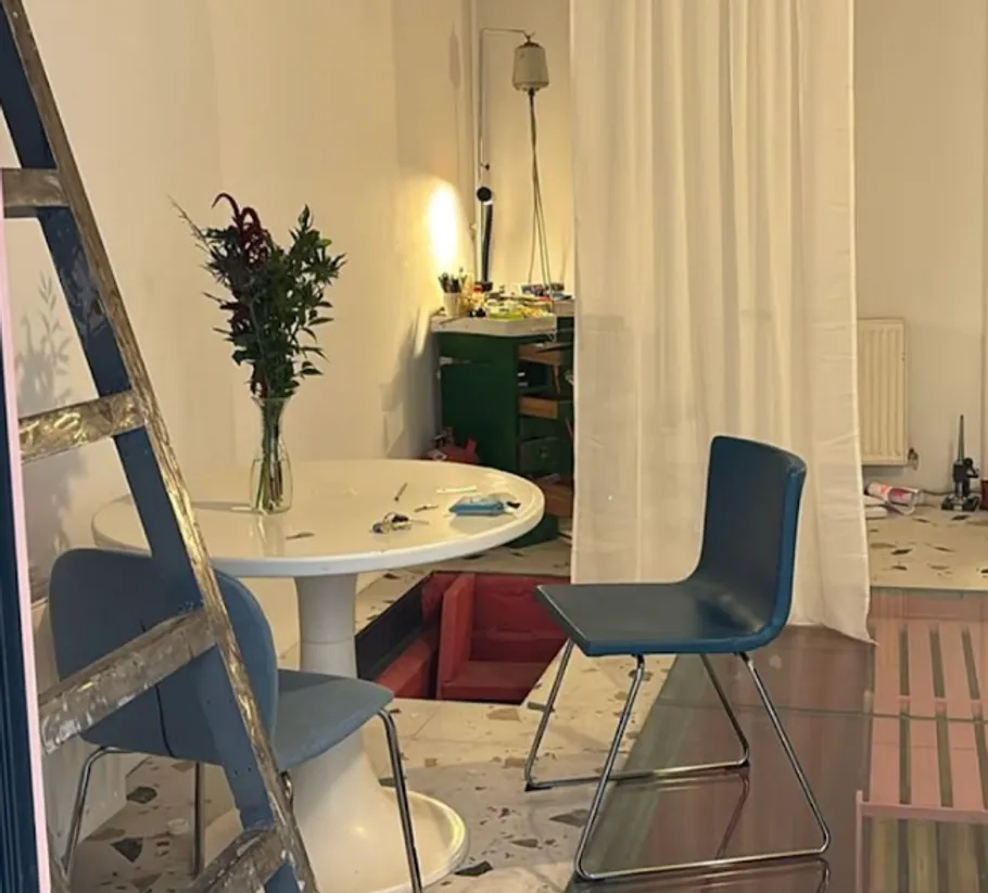 Room with table, chairs, ladder, and curtain.
