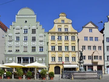 Bunte historische Gebäude stehen um einen Brunnen.