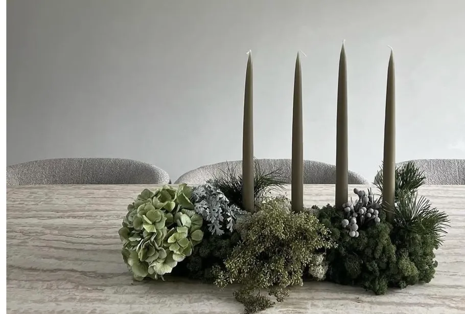 Four candles in decorative greenery centerpiece.