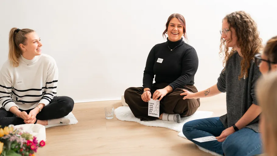 Three people sitting in a circle, smiling.