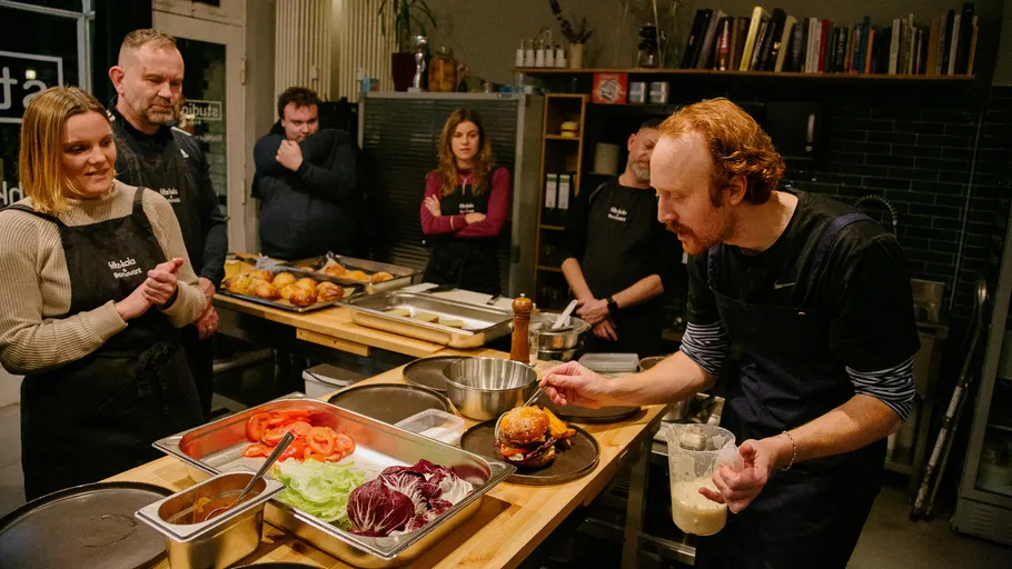Chef demonstrates sandwich preparation to attentive group.