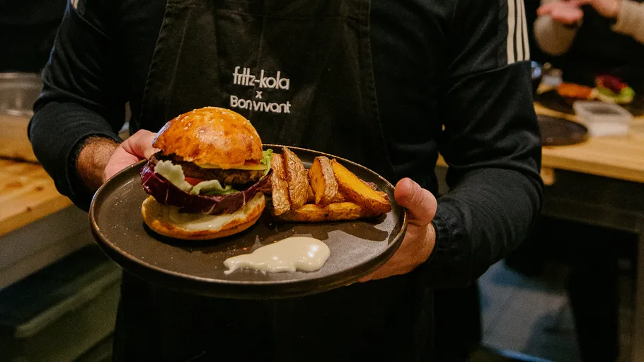 Person hält Burger und Pommes auf Teller.