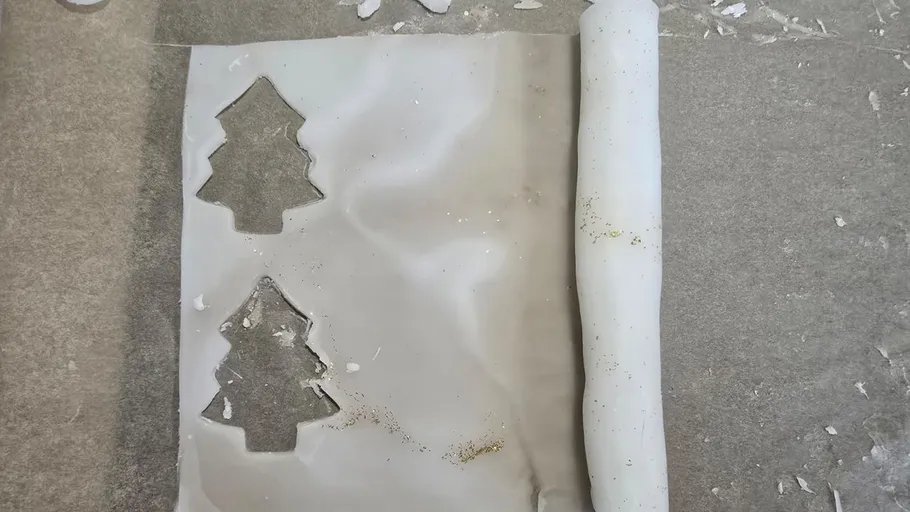 Rolled-out dough with tree cutouts on sheet.