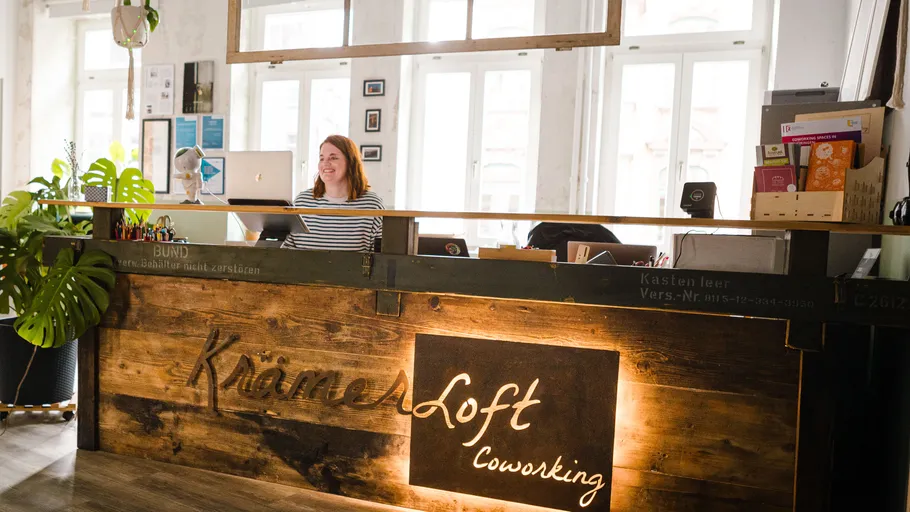 Frau lächelt am Empfangsschalter im Coworking-Bereich.