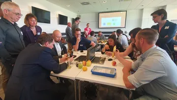 Personen untersuchen Obst und Laptops im Besprechungsraum.
