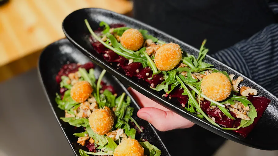 Plates with salad, croquettes, nuts served.