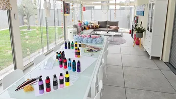 Kunstbedarf auf Tisch in hellem Wintergarten.