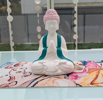 Ceramic Buddha statue on colorful mat indoors.