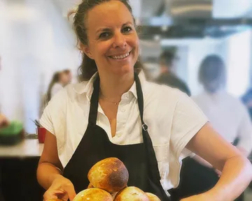Woman holding bread in kitchen setting.