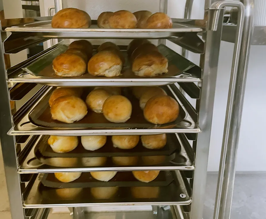 Bread rolls cooling on metal racks in kitchen.