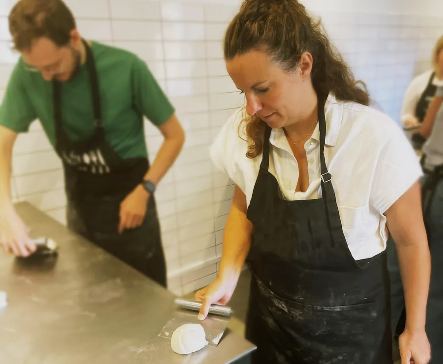 Two people shaping dough in a kitchen.