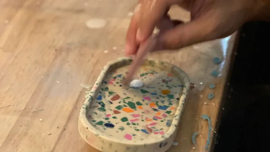 Hand stirs paint in colorful tray.