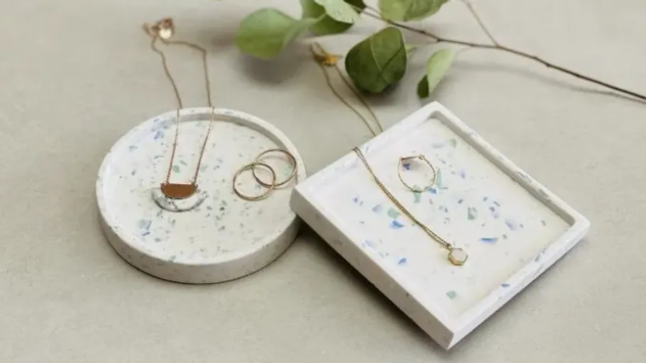 Goldschmuck auf Terrazzo-Tabletts präsentiert.