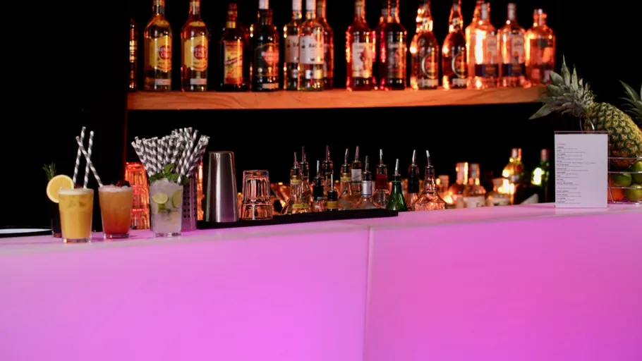 Cocktailbar mit pinker Beleuchtung und Flaschen.