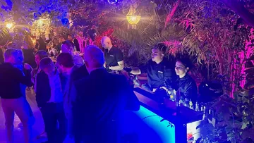 Bartenders serving drinks at outdoor evening event.
