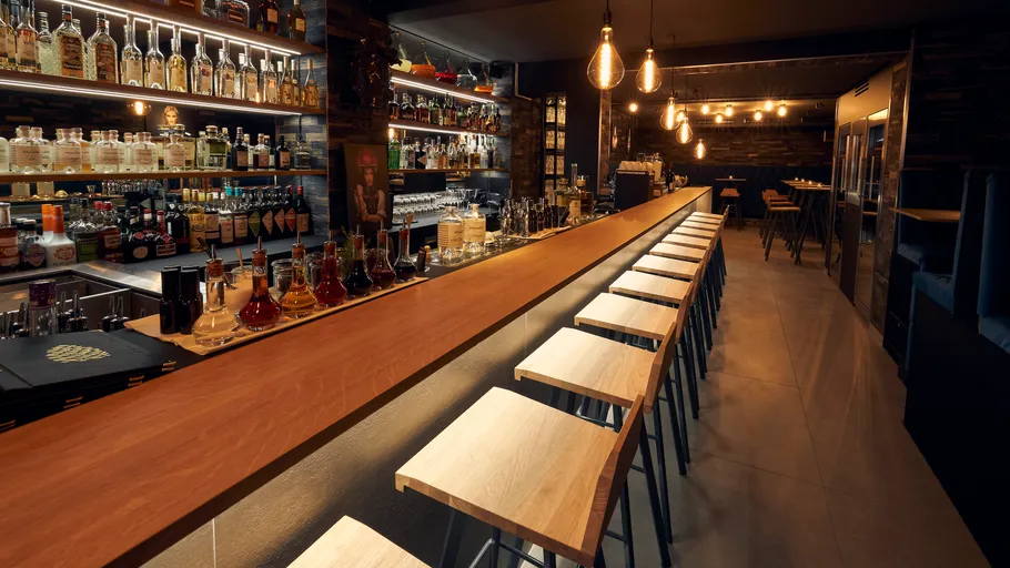 Empty bar with stools and illuminated shelves.