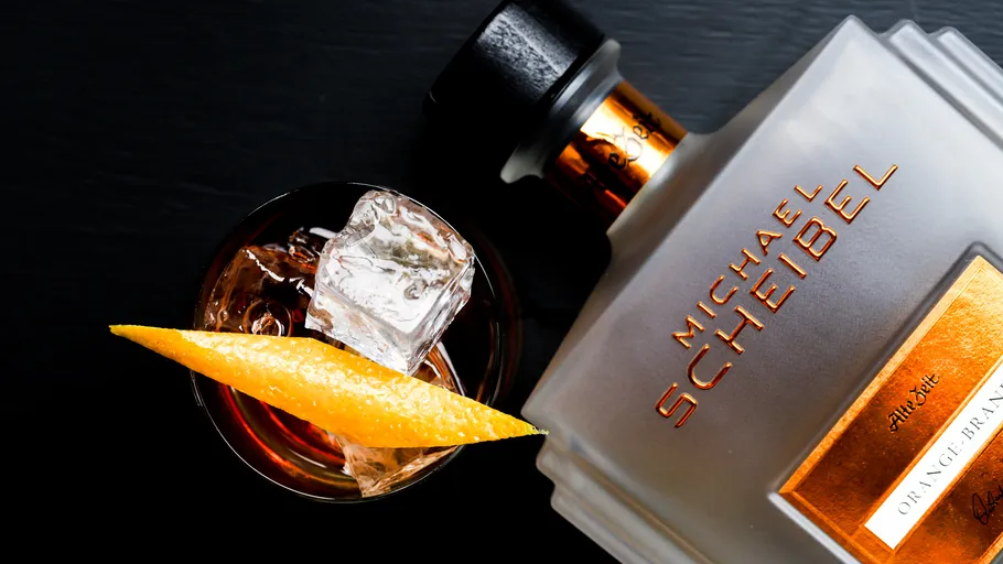 Flasche neben Cocktail mit Orangenscheibe.