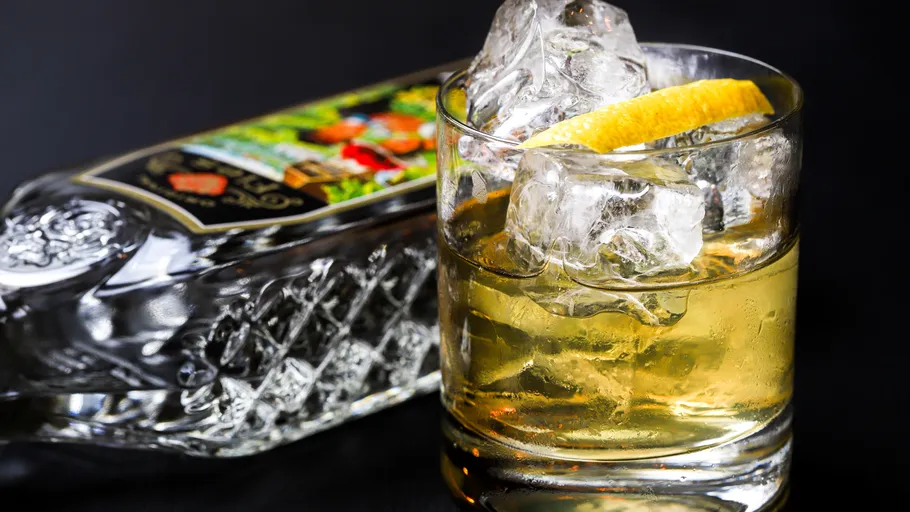 Glas mit Eis und Zitrone neben Flasche.