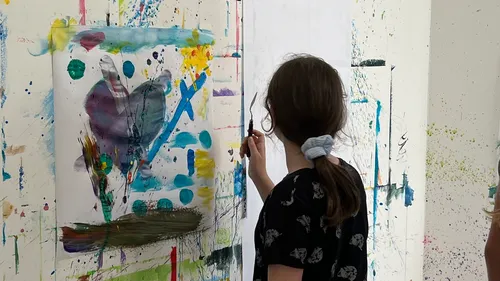 Child painting abstract artwork in a studio.