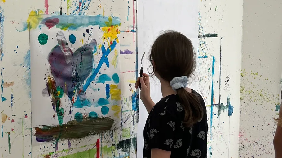 Child painting abstract artwork in a studio.