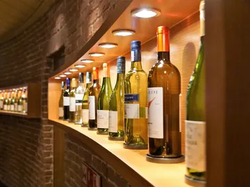 Bottles are on a shelf, illuminated in a wine cellar.