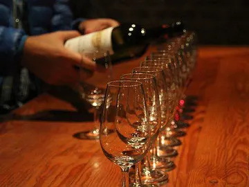 A man pours wine into glasses on a table.