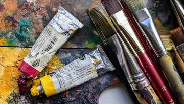 Farb-Tuben und Pinsel auf einer Palette.