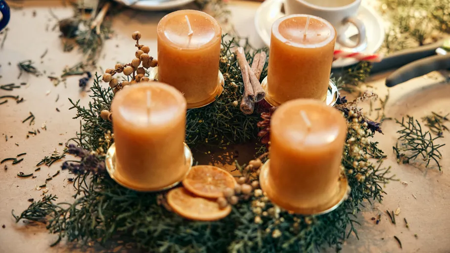 Vier Kerzen auf einem dekorativen Adventskranz.