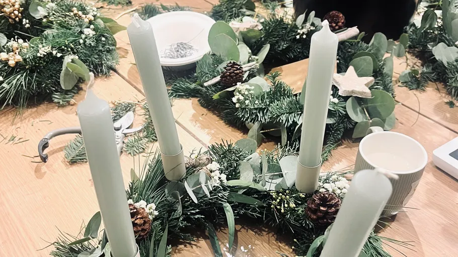 Four candles on decorative wreaths on table.