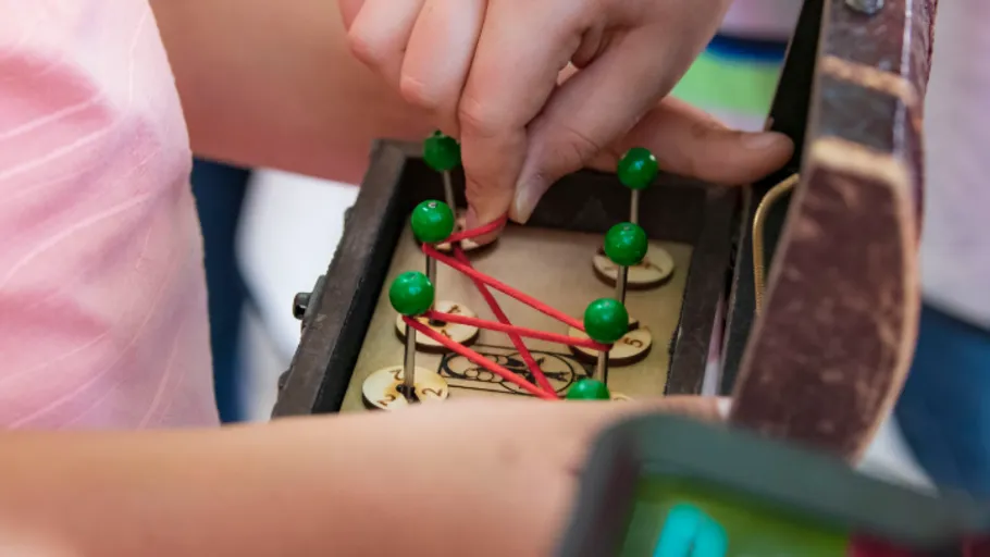 Person solving puzzle with rubber bands crate.