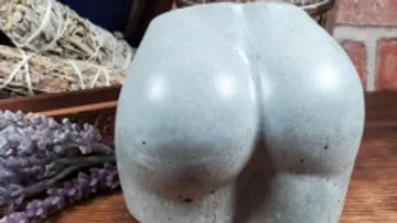 Sculpted buttocks displayed on wooden surface.