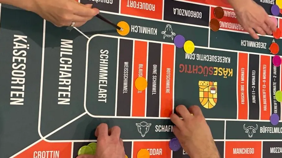 Hände platzieren Spielsteine auf einem Käsebrettspiel.