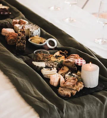 Cheese platter with bread and candle on table.