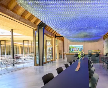 Modern room with long table and unique ceiling.