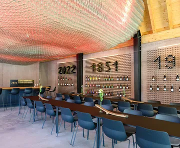 Modern bar with wine bottles and ceiling glasses.