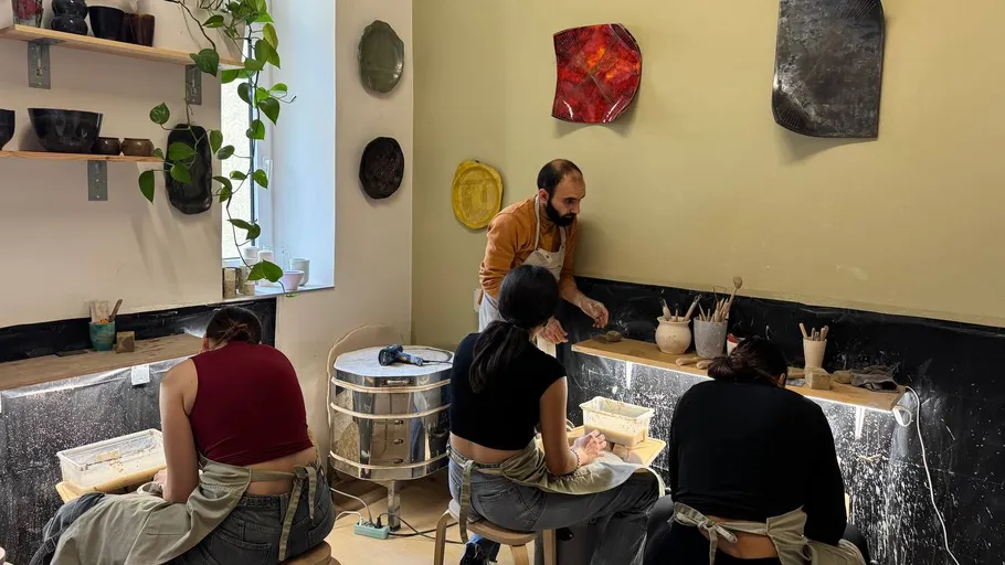 Personen arbeiten an Töpferscheiben im Studio.