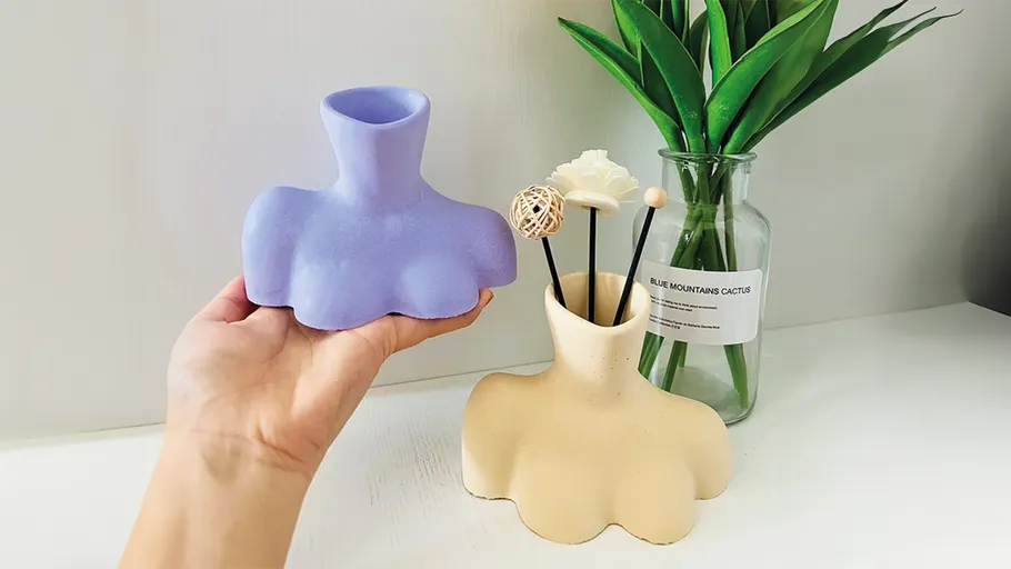 Lila Vase neben beiger Vase mit Dekoration gehalten.