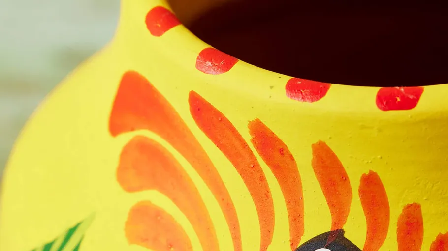 Close-up of painted yellow pottery with designs.